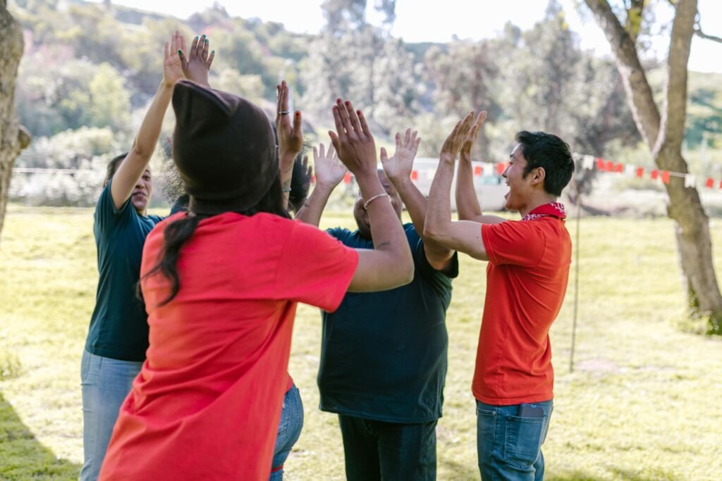 pexels-photo-7551751-7551751 Diverse friends in park high-fiving during fun team-building exercise.